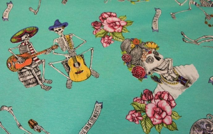Tela loneta con calaveras, esqueletos y rosas sobre fondo verde esmeralada, detalle guitarrista.Ancho 2.80 metros-Conchi Berguño